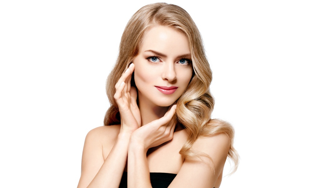 Голубоглазая блондинка с руками у лица на белом фоне