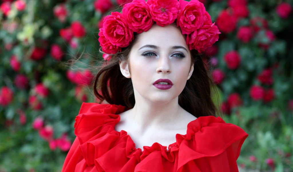 Яркая девушка в красном платье с венком из роз на голове