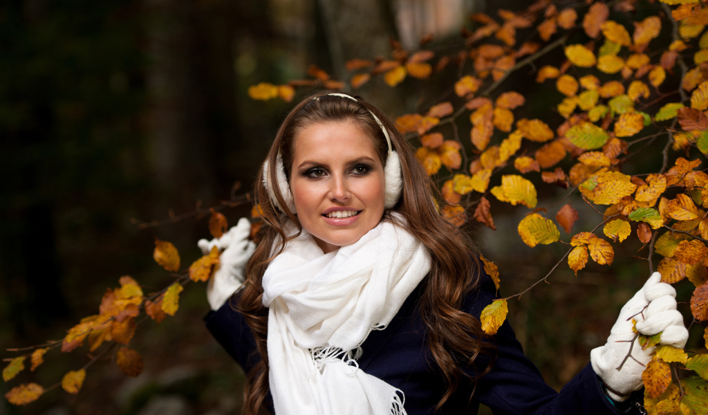 Девушка шатенка с белым шарфом стоит у дерева с желтыми листьями