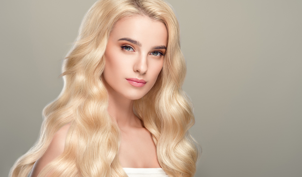 Милая длинноволосая блондинка на сером фоне