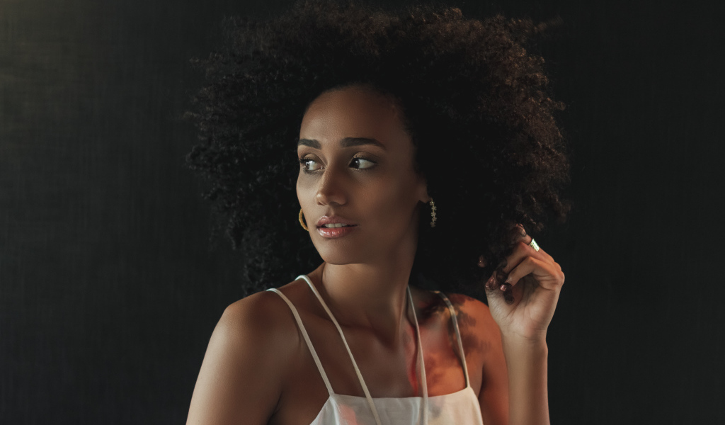 Темнокожая девушка с красивыми волосами на сером фоне