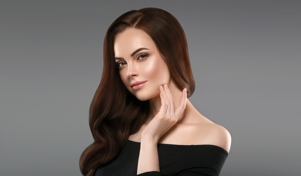 Нежная длинноволосая шатенка в черном платье на сером фоне