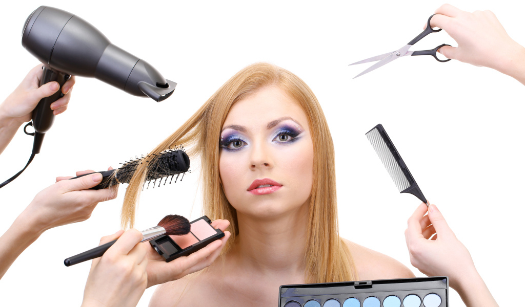 Девушке делают макияж и прическу на белом фоне