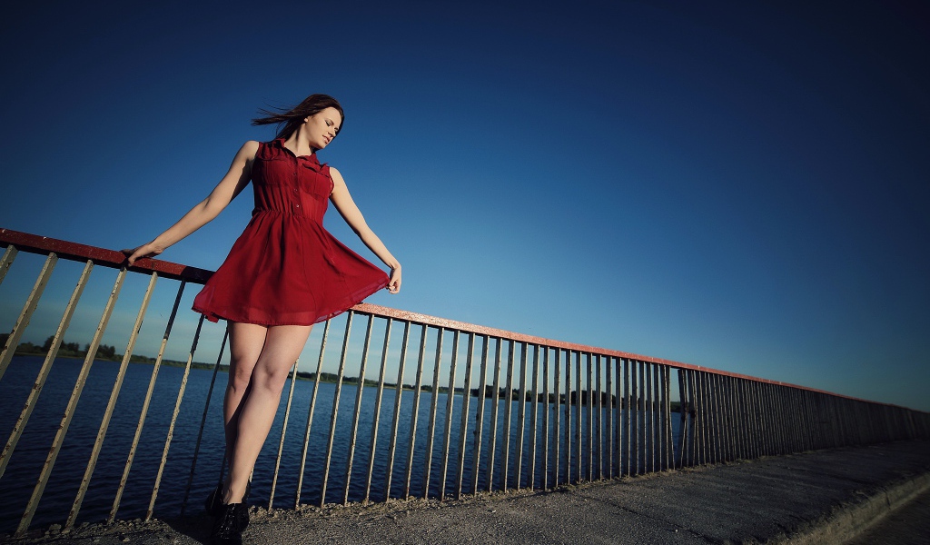Девушка в коротком красном платье на мосту 