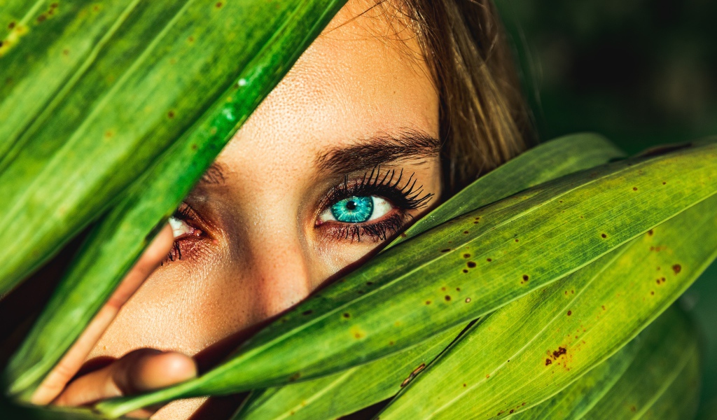 Девушка с голубыми глазами в зеленых листьях 