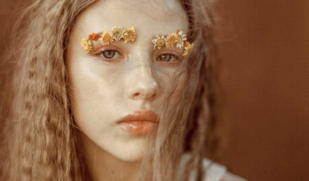 Девушка с цветами на бровях крупным планом