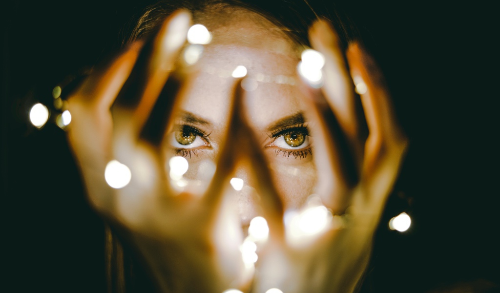 Руки с гирляндой у лица девушки