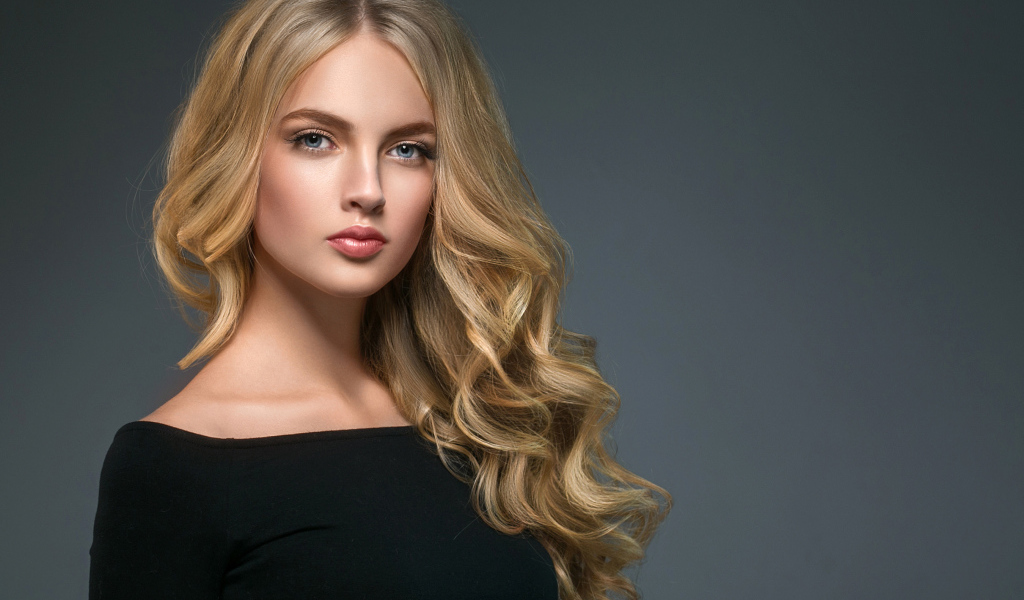 Длинноволосая блондинка с голубыми глазами на сером фоне