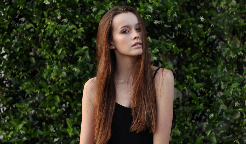 Длинноволосая шатенка на фоне зеленых зарослей