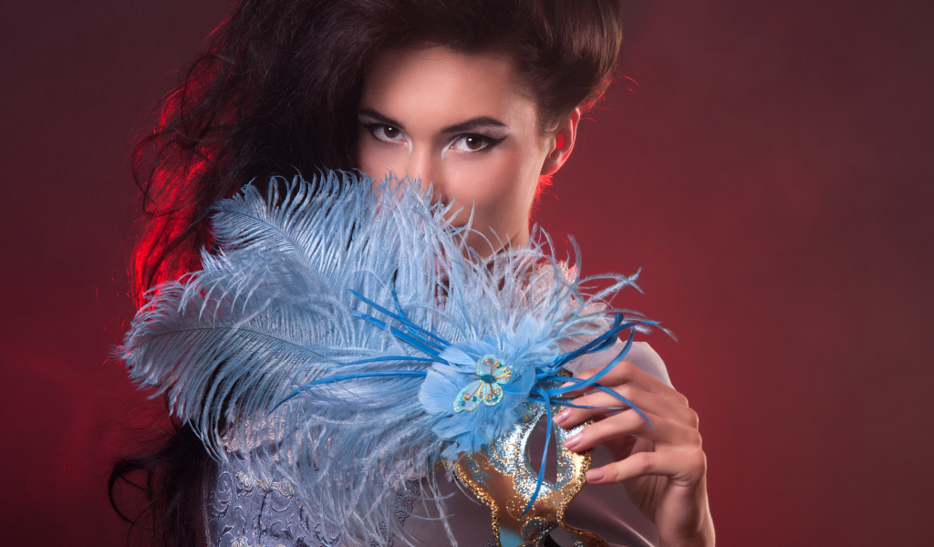 Длинноволосая девушка с маской с перьями в руке