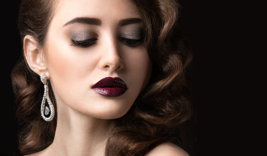 Длинноволосая девушка с ярким макияжем на черном фоне