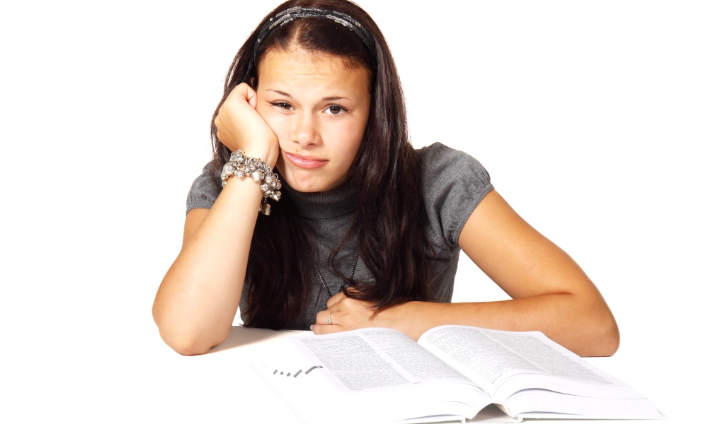 Грустная девушка читает книгу на белом фоне