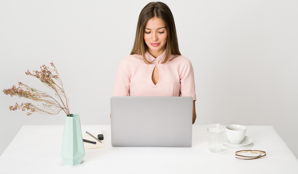 Умная девушка за ноутбуком на сером фоне