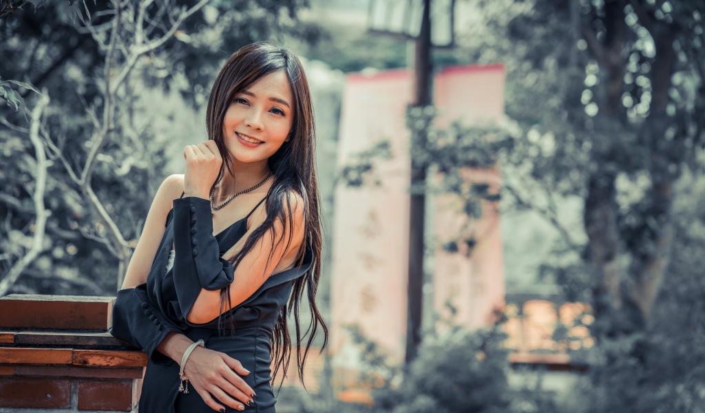 Улыбающаяся девушка азиатка в черном платье