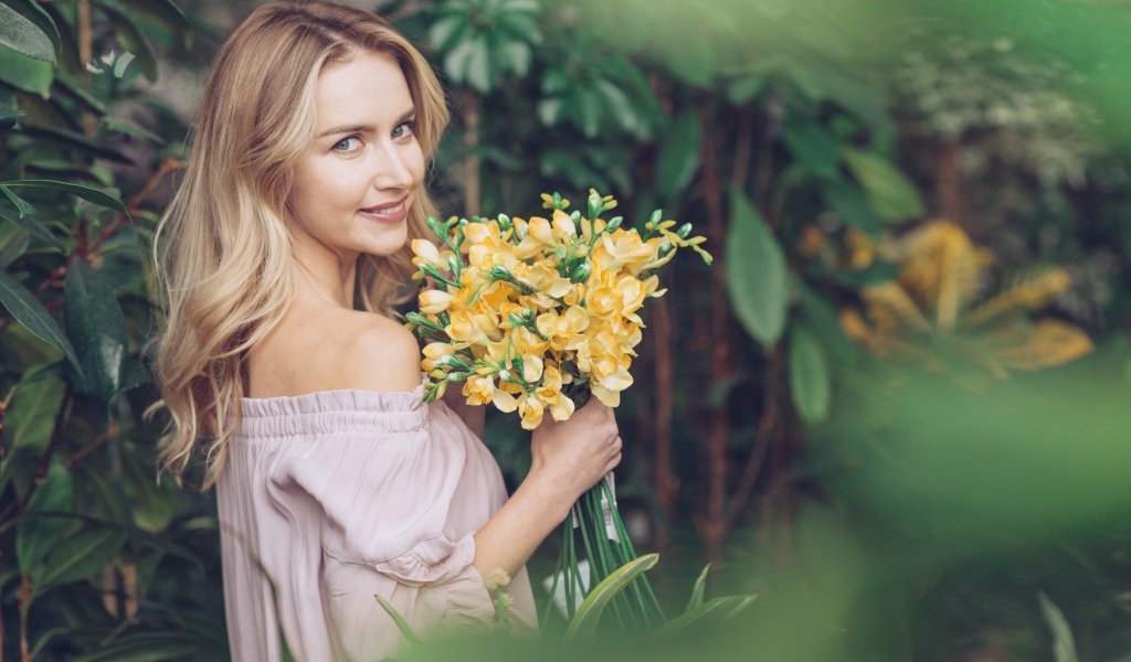 Улыбающаяся блондинка с букетом хризантем в руках