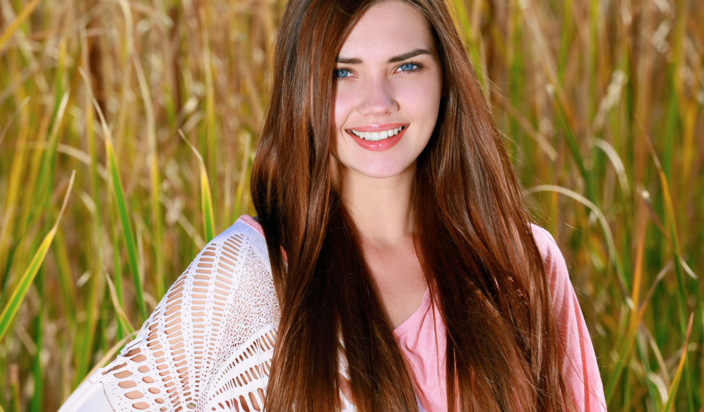 Улыбающаяся голубоглазая шатенка на поле