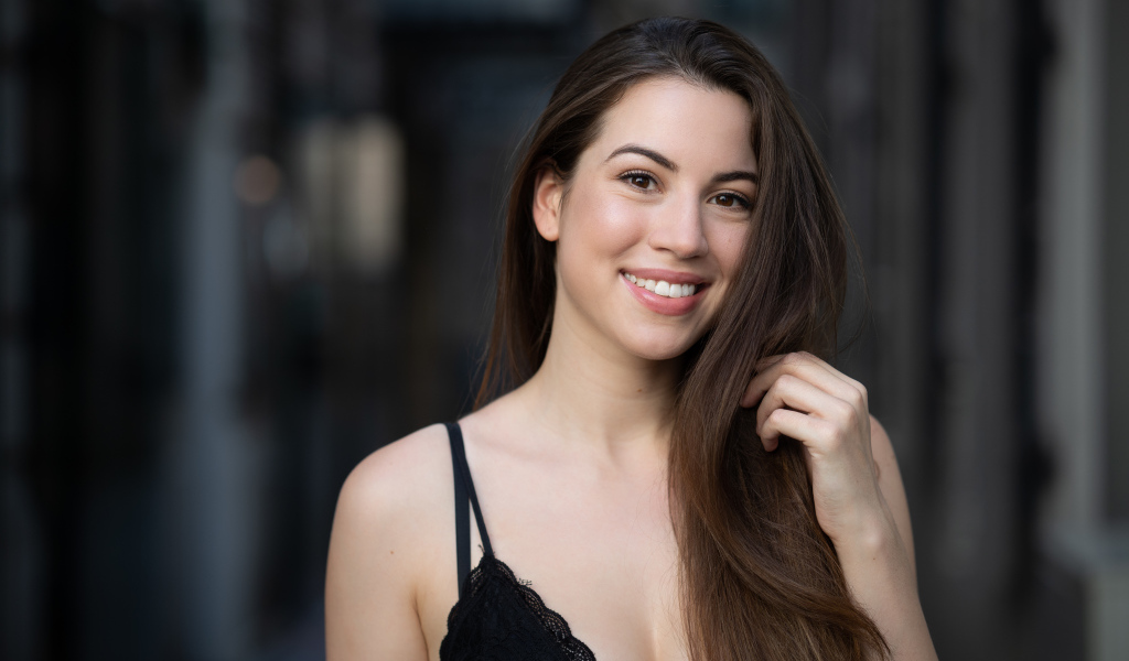 Улыбающаяся девушка держит длинные волосы