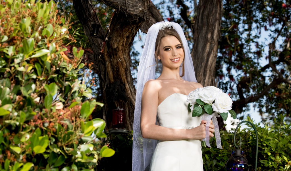 Улыбающаяся девушка в свадебном платье с букетом