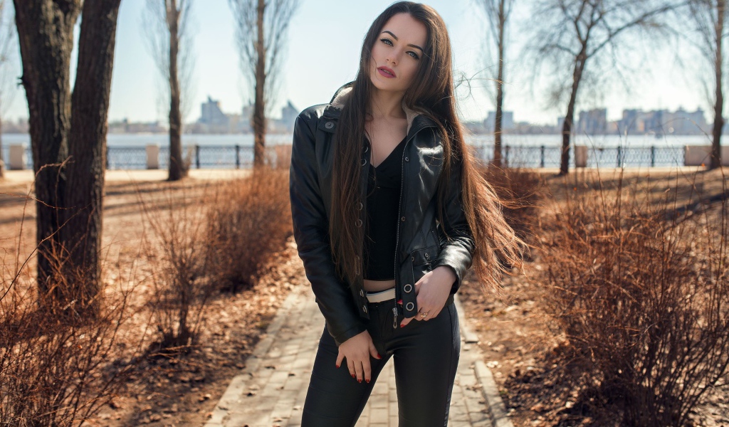 Стильная девушка в черной куртке в парке 