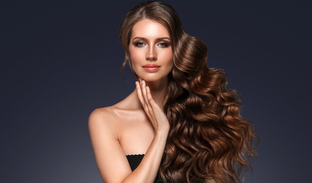 Стильная девушка с красивыми длинными волосами на сером фоне