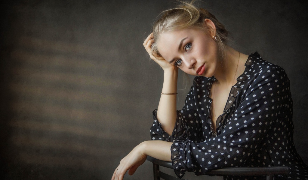 Нежная девушка блондинка сидит на стуле