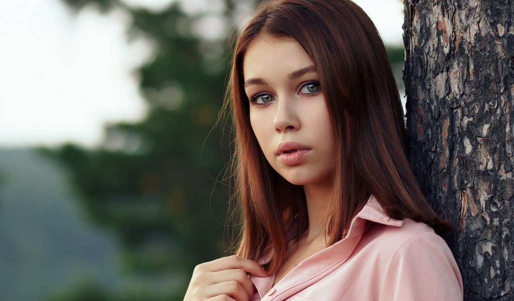 Нежная девушка стоит у дерева