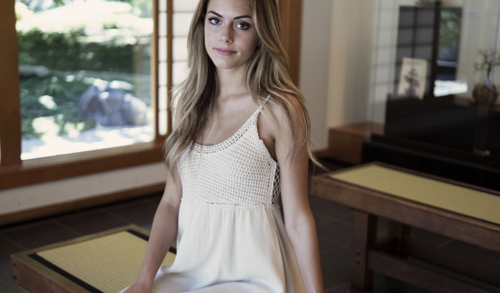 Девушка в белом сарафане сидит на лавке 