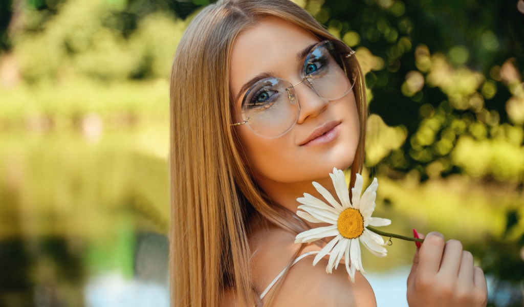 Девушка в очках с ромашкой в руке 