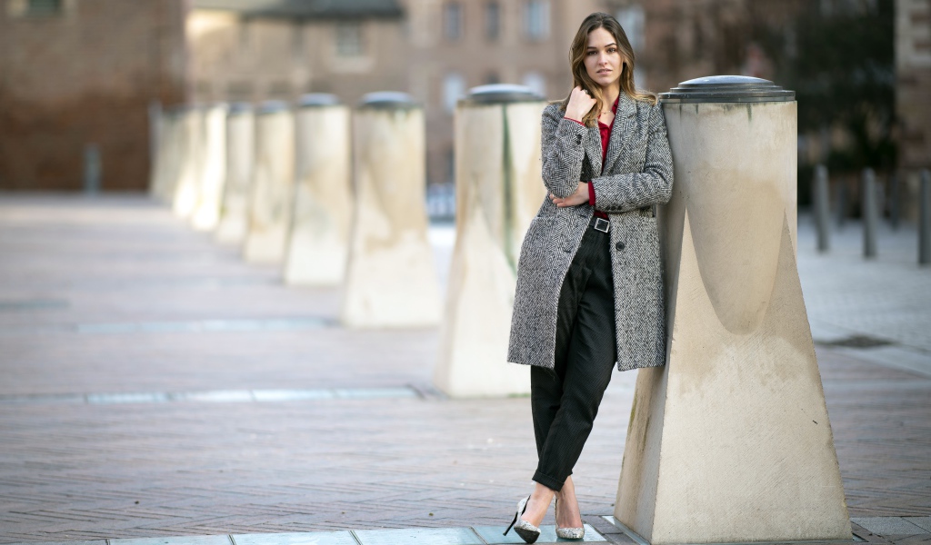 Девушка стоит в сером пальто 