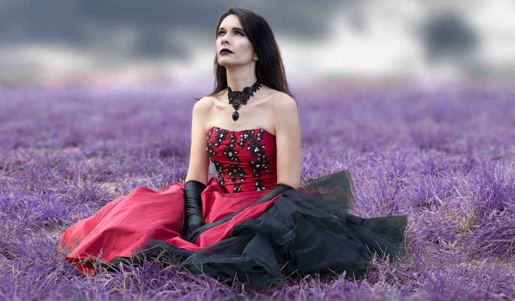 Девушка с макияжем в красивом платье сидит на траве