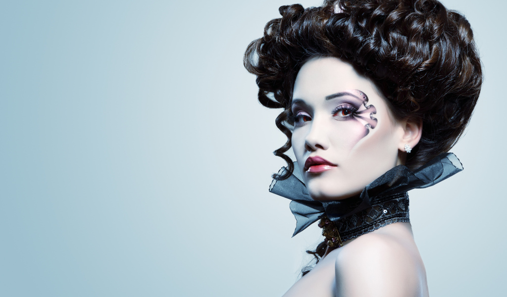 Девушка с необыной прической и макияжем на сером фоне