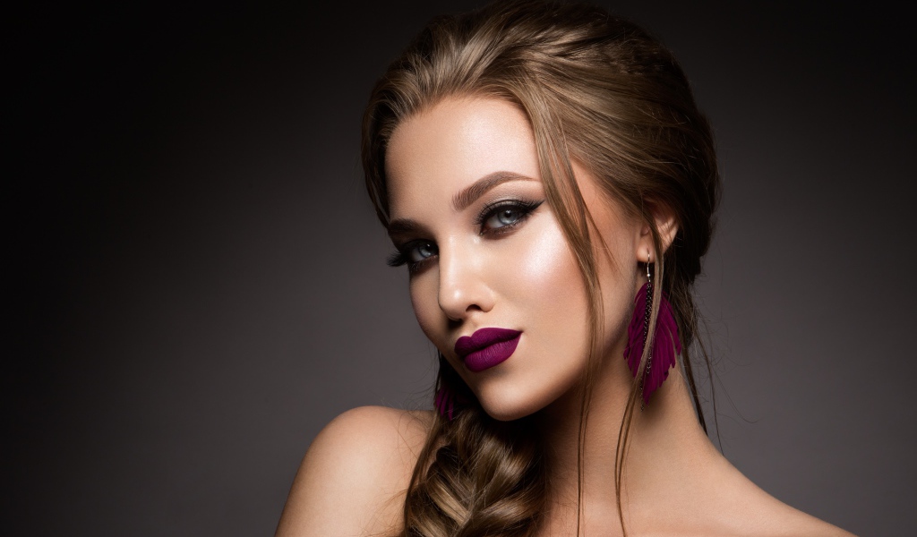 Девушка с ярким макияжем и косой на сером фоне