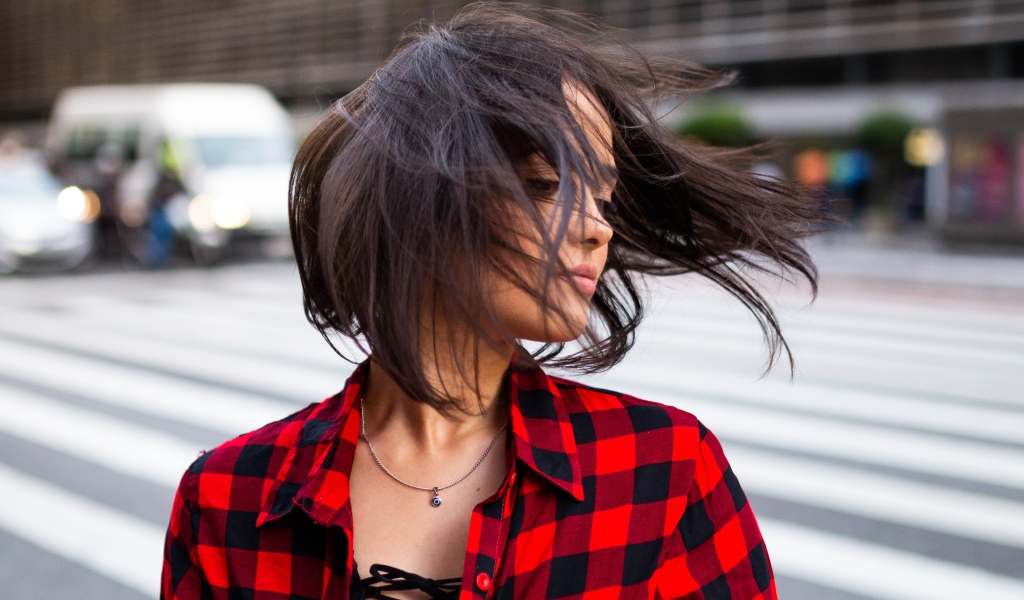 Ветер развивает волосы красивой шатенки в клетчатой рубашке