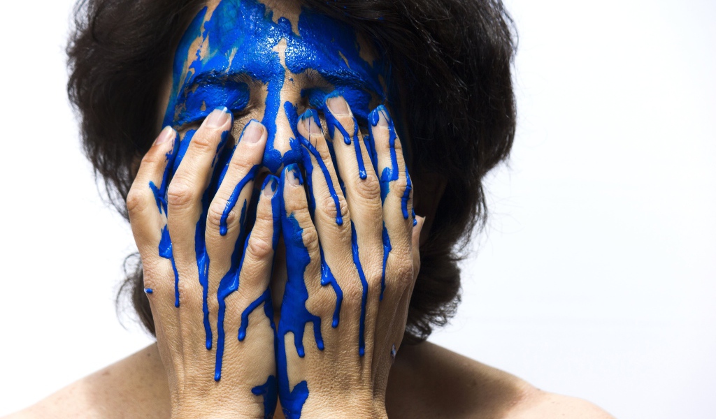 Лицо и руки женщины в синей краске