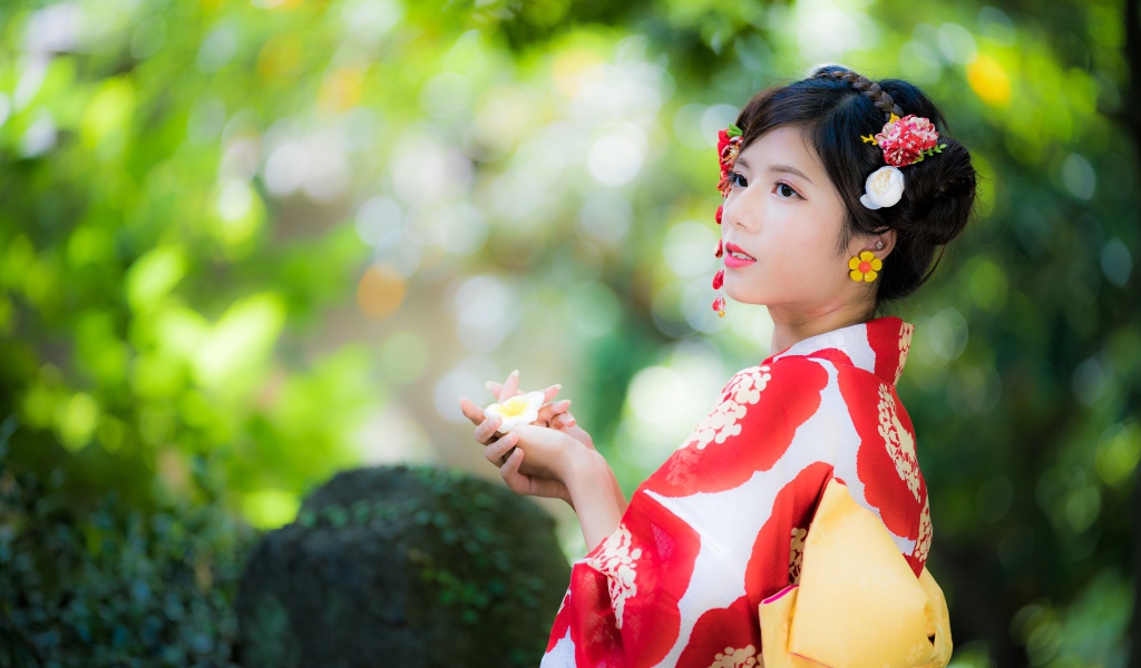 Молодая девушка азиатка в кимоно с цветами в волосах 