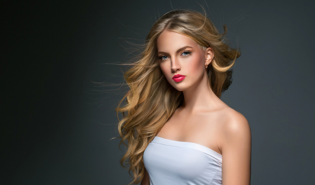 Молодая красивая голубоглазая блондинка на сером фоне