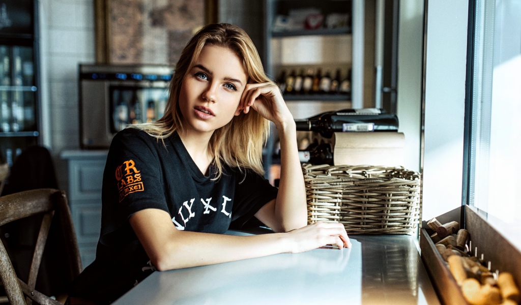 Молодая голубоглазая девушка сидит в кафе