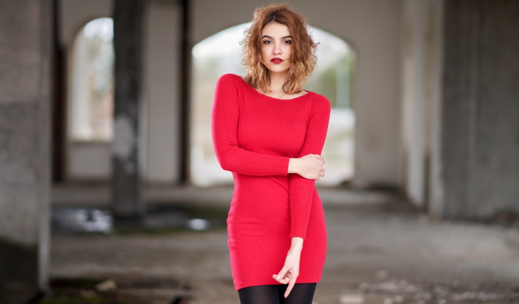 Молодая девушка в красном платье в старом здании