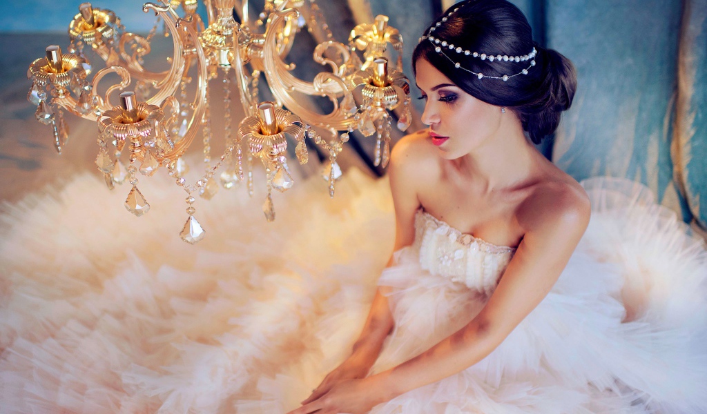 Молодая девушка в белом платье у красивой  люстры