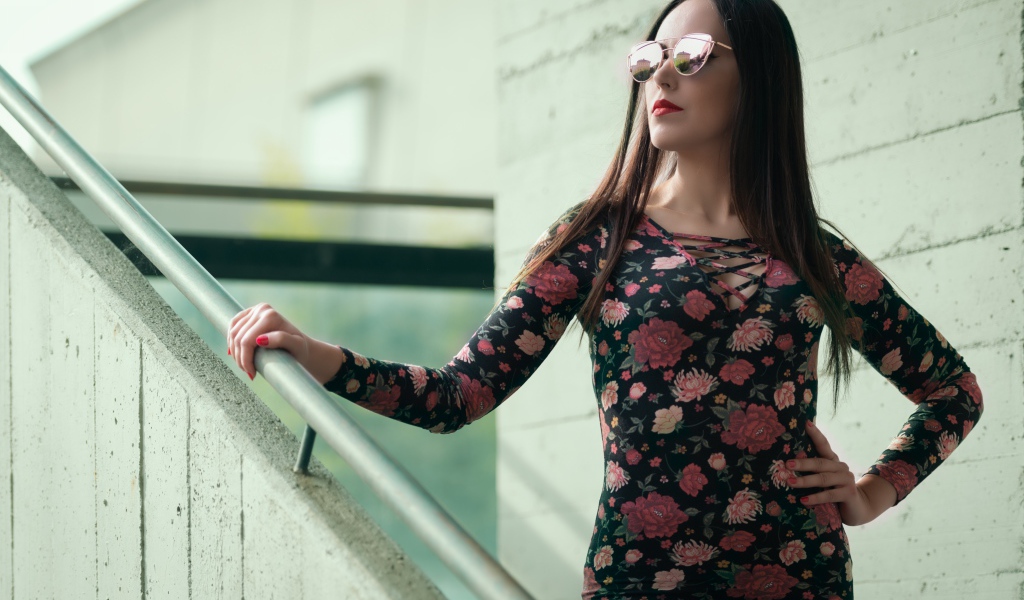 Молодая девушка в солнечных очках стоит на ступеньках