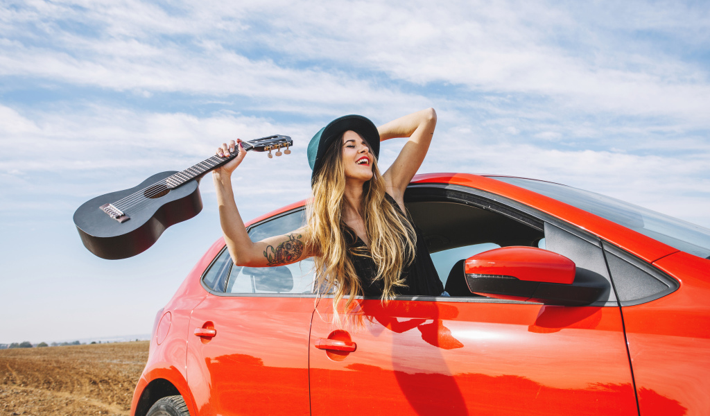 Молодая девушка с гитарой в красной машине летом