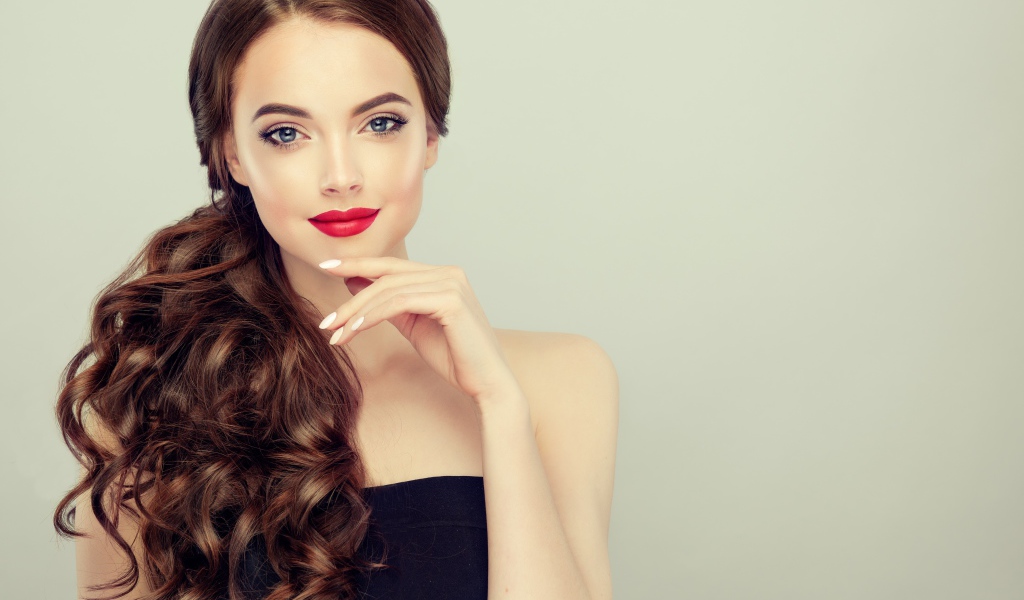 Молодая девушка с красивыми волосами на сером фоне