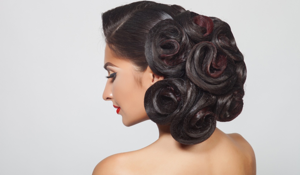 Молодая девушка с красивой прической на сером фоне