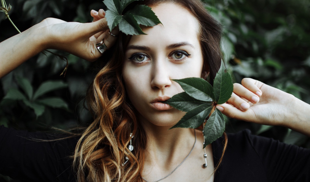 Молодая девушка с зелеными листьями в руках 