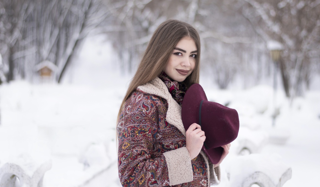 Молодая длинноволосая девушка шатенка с шляпой в руках зимой