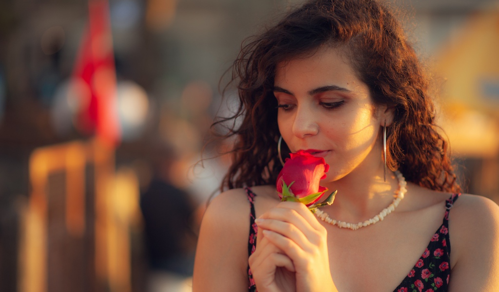 Молодая нежная девушка с красной розой в руке