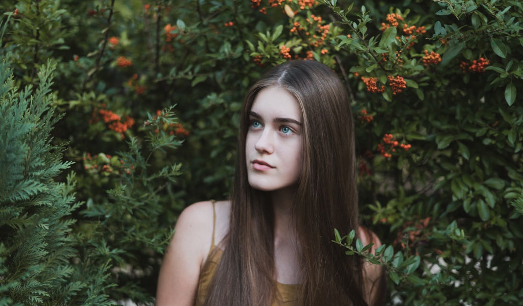 Молодая нежная девушка с длинными волосами в зеленых зарослях 