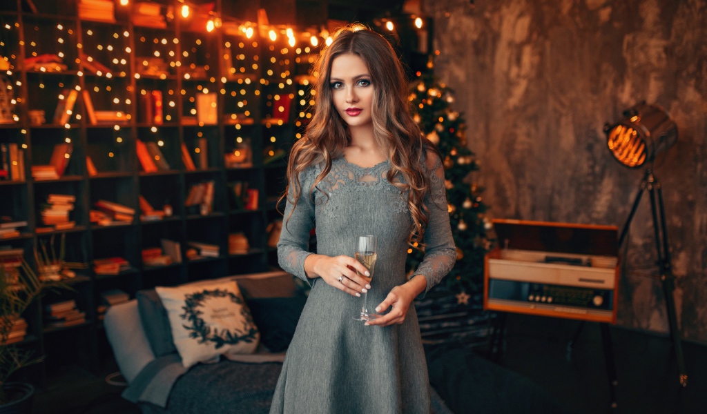 Beautiful girl with a glass of champagne in a room decorated with a garland