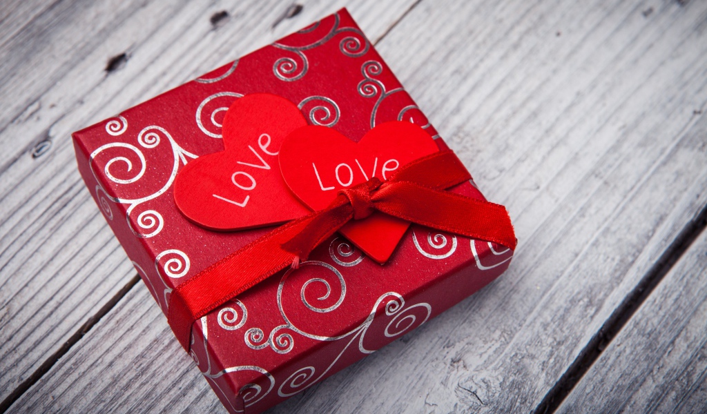 Подарок с красными сердечками на деревянном столе 