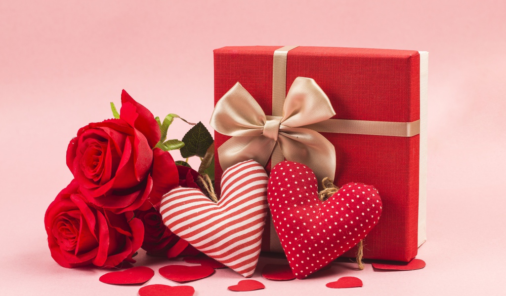 Three red roses with hearts and gift on a pink background